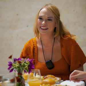 woman wearing her pureAir Personal smiling at the dinner table. 